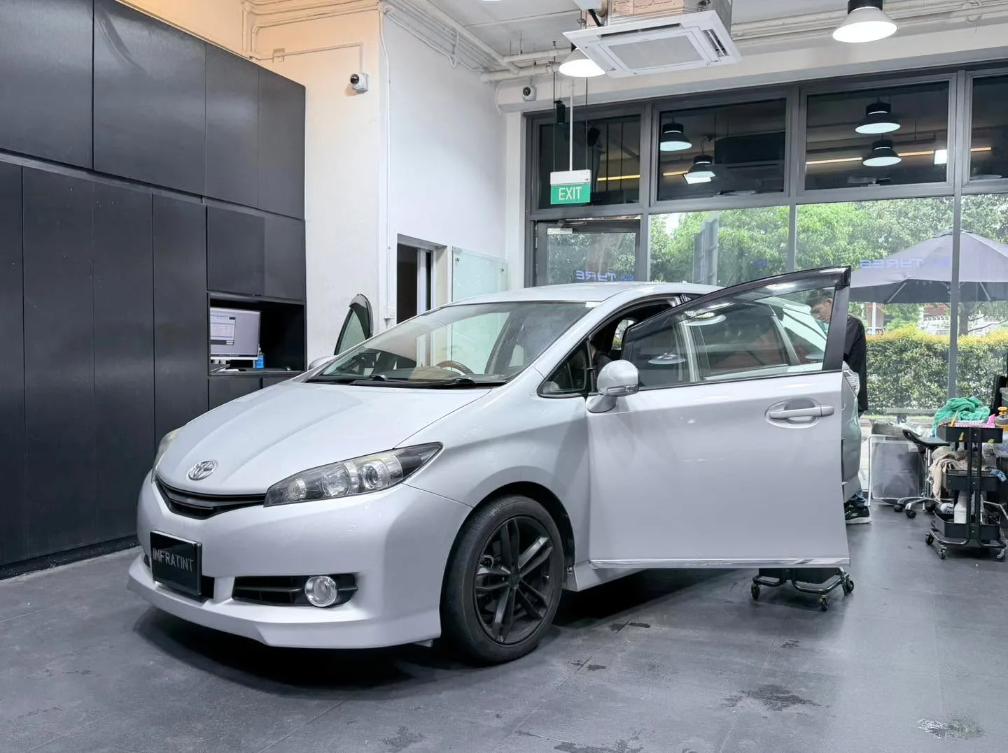 A black Honda sedan with doors open and a roof rack, undergoing window tinting.
