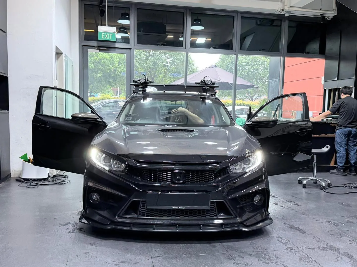 A black Honda sedan with doors open and roof rack during tinting work.