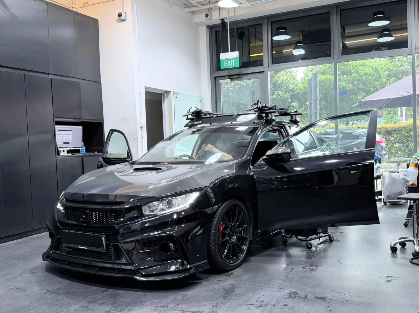A black Honda sedan with doors open and roof rack inside the workshop.