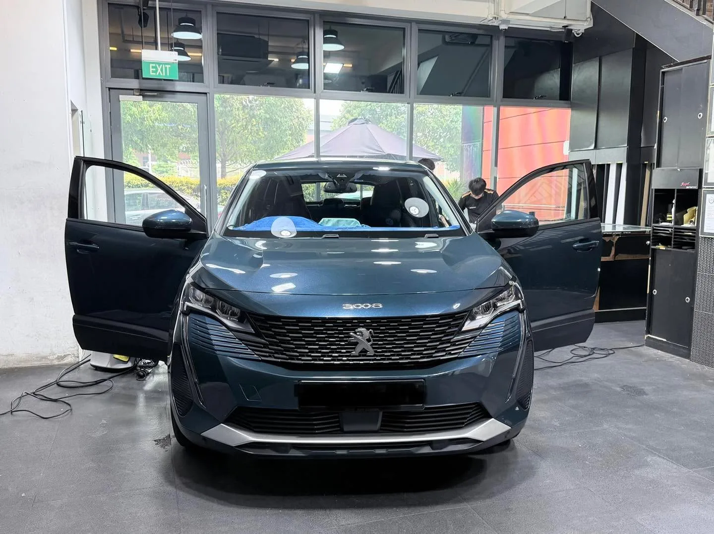 A grey Peugeot 3008 SUV with both front doors open in the workshop.