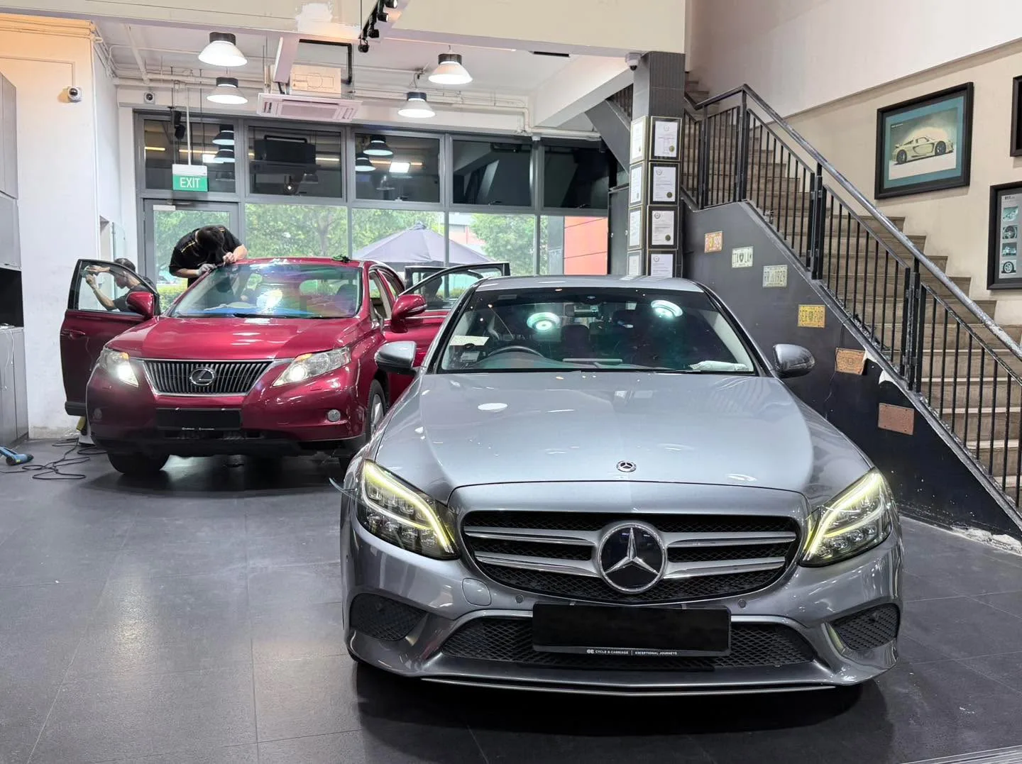 A silver Mercedes-Benz sedan and burgundy Lexus sedan undergoing tinting work.