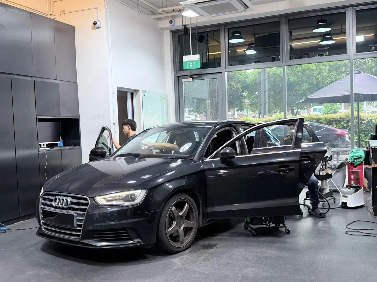 A white Lexus sedan with doors open, staff applying film to windows.