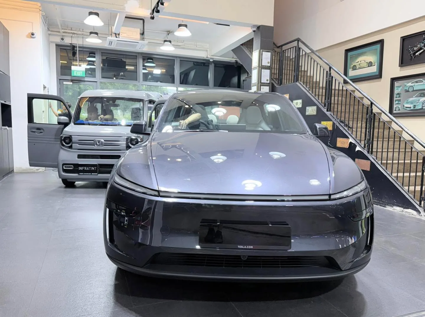 A silver electric saloon parked indoors with its doors open.