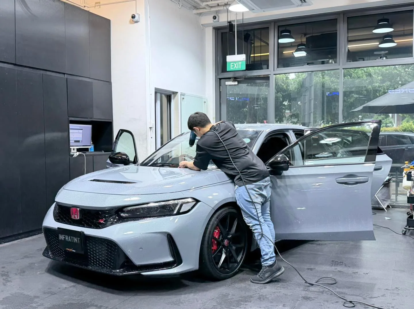 A white sports coupe parked in the workshop with its door open.