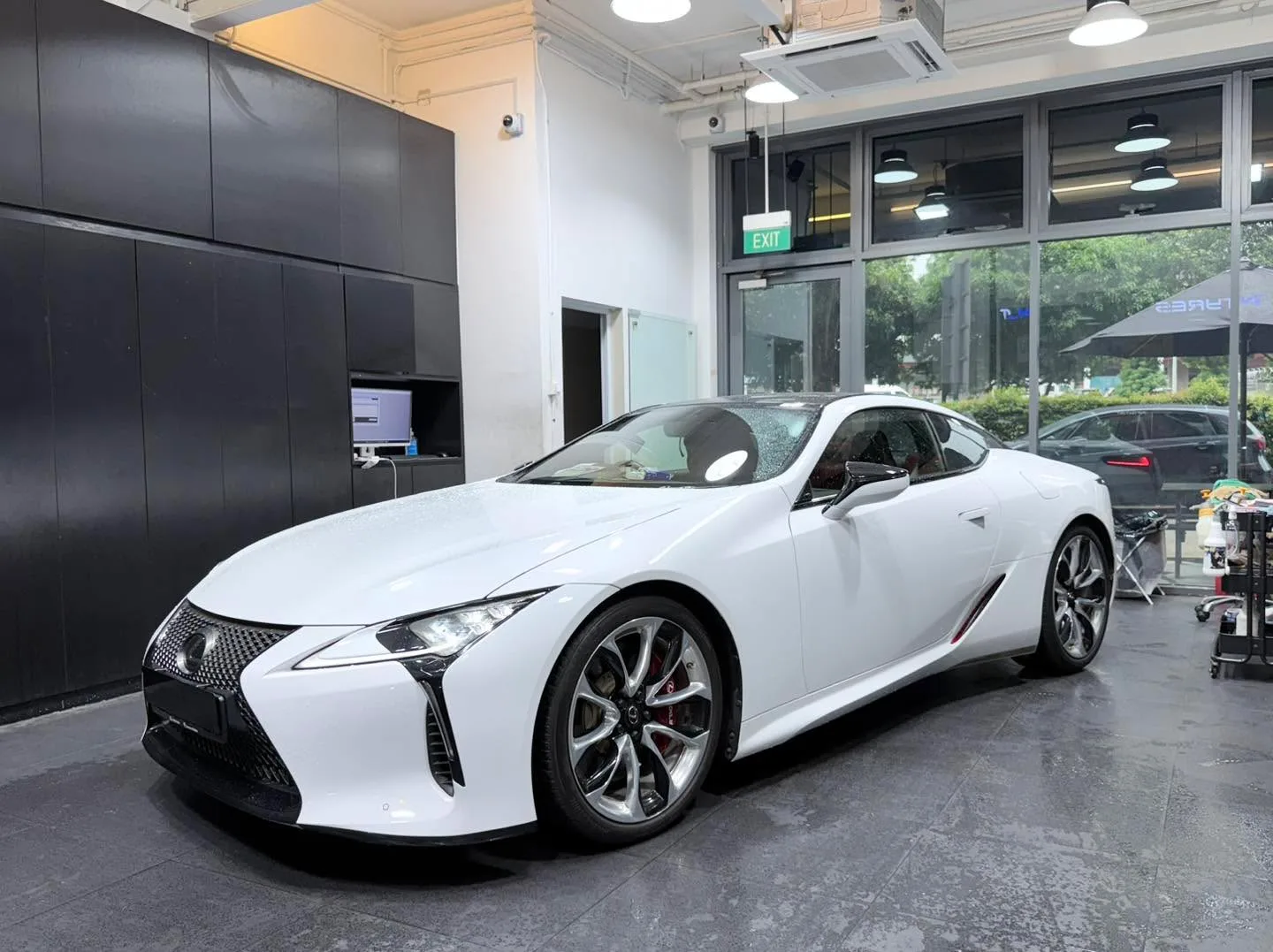 A white sports coupe in profile view inside the workshop.