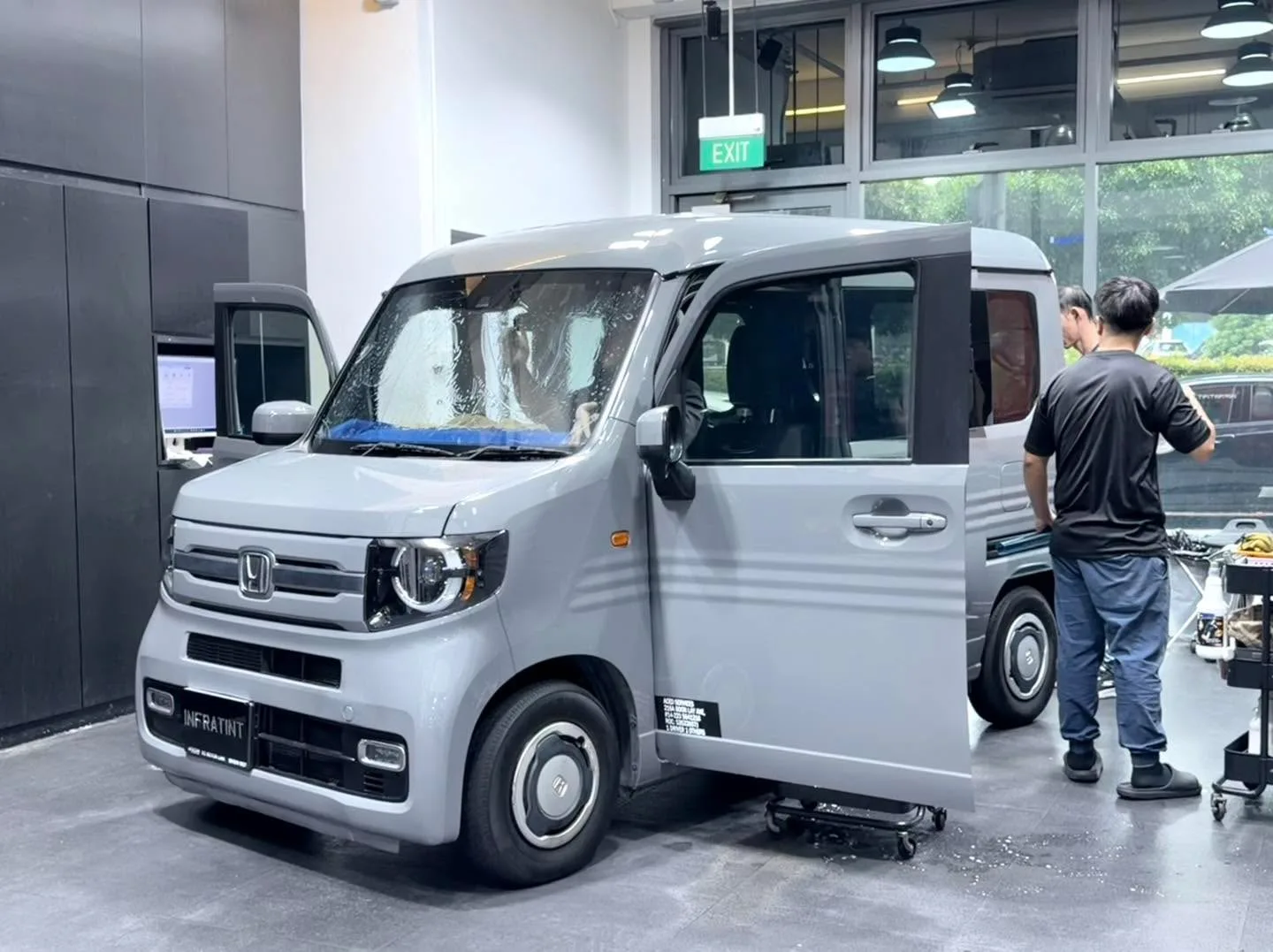 A silver mini kei vehicle being tinted, viewed from the side with doors open.