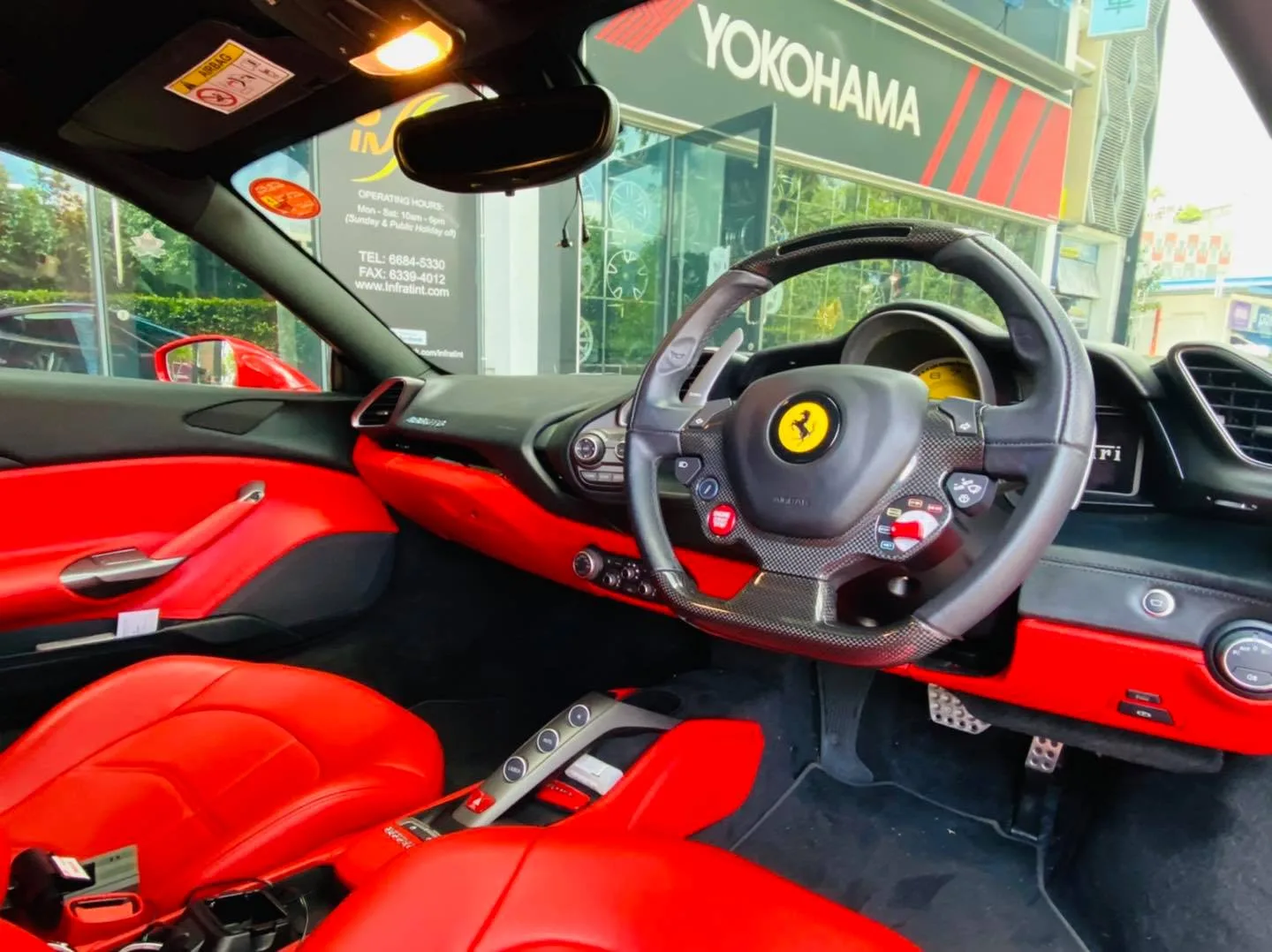 Red leather interior and carbon steering wheel of a Ferrari at Infratint Singapore