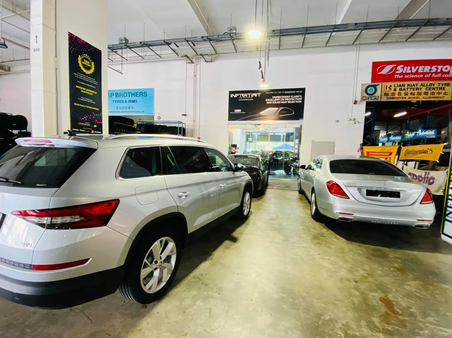 Silver Skoda SUV and silver Mercedes-Benz sedan inside Infratint Singapore for window tinting