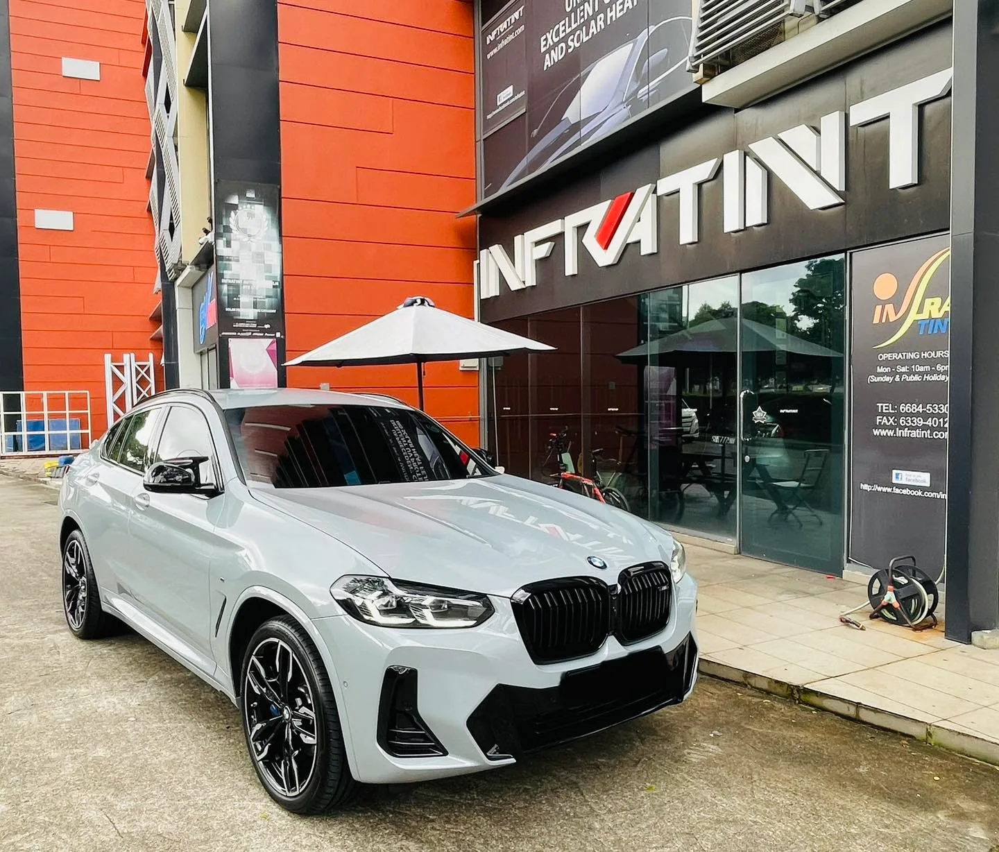 Grey BMW X4 front three-quarter view outside the Infratint Singapore shopfront