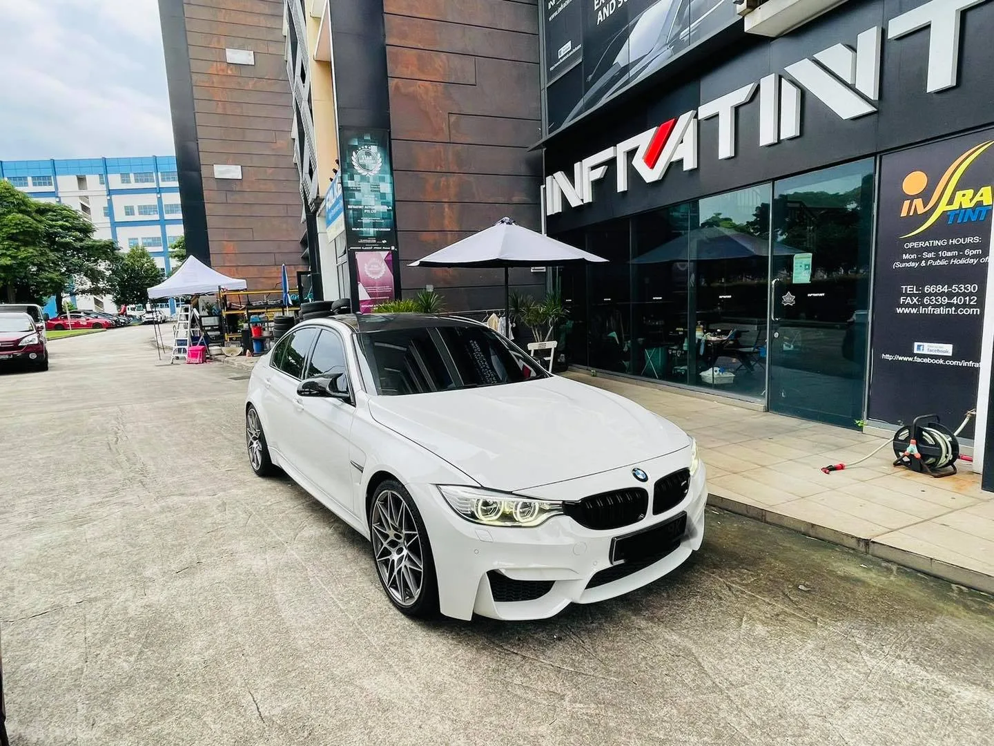 White BMW M3 sedan parked outside the Infratint Singapore shopfront