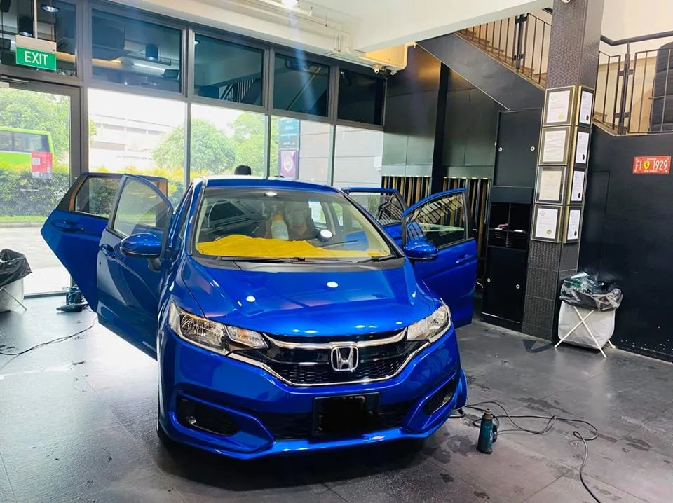 Blue Honda Fit with doors open in the install bay at Infratint Singapore
