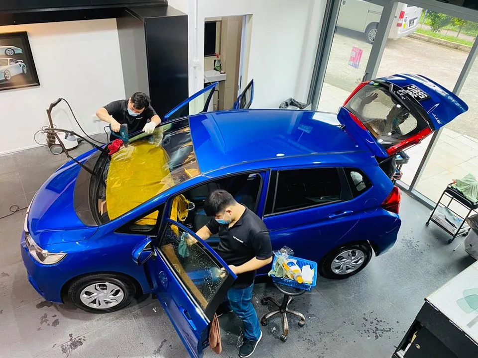 Overhead view of two technicians tinting a blue Honda Fit at Infratint Singapore
