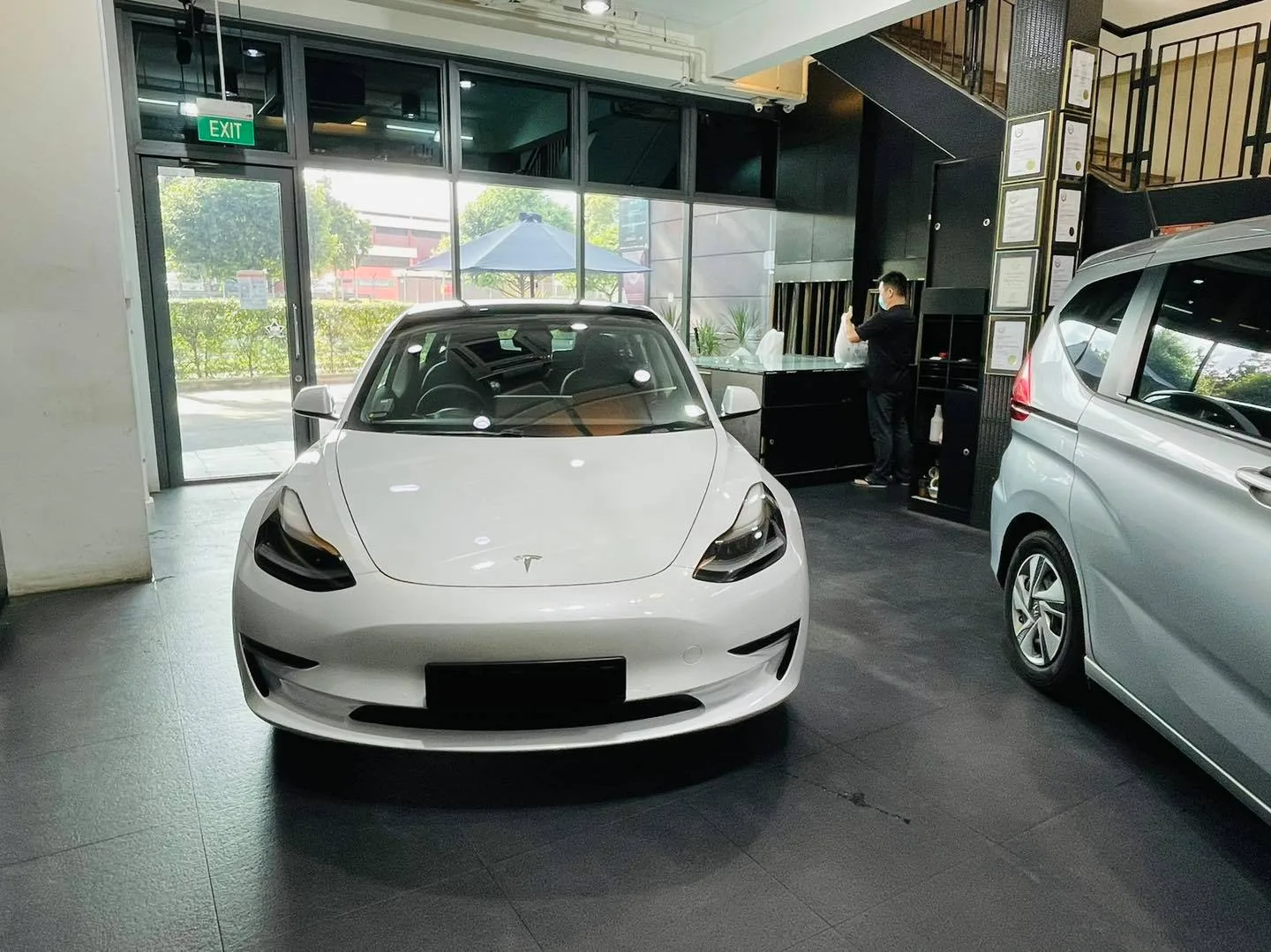 White Tesla Model 3 front view beside a silver Honda Freed at Infratint Singapore