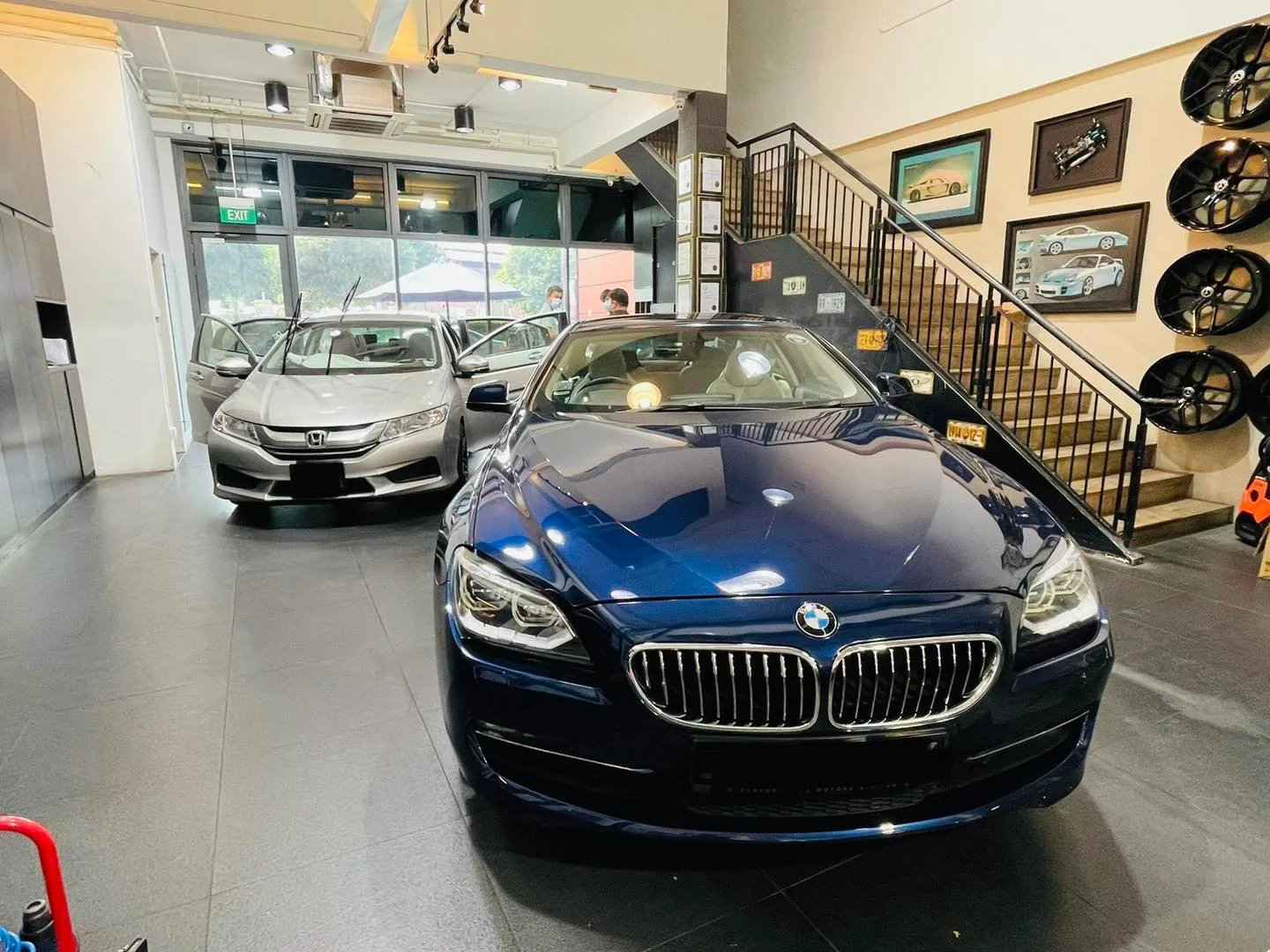 Blue BMW coupe and silver Honda sedan in the Infratint Singapore showroom for window tinting