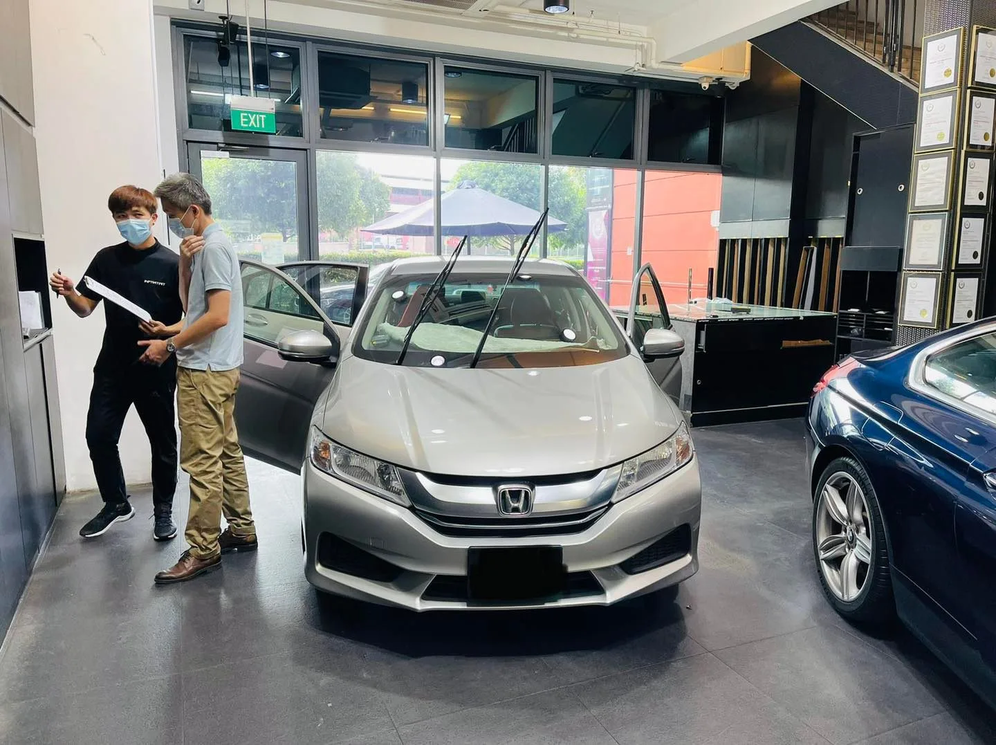 Staff consulting a customer next to a silver Honda sedan at Infratint Singapore