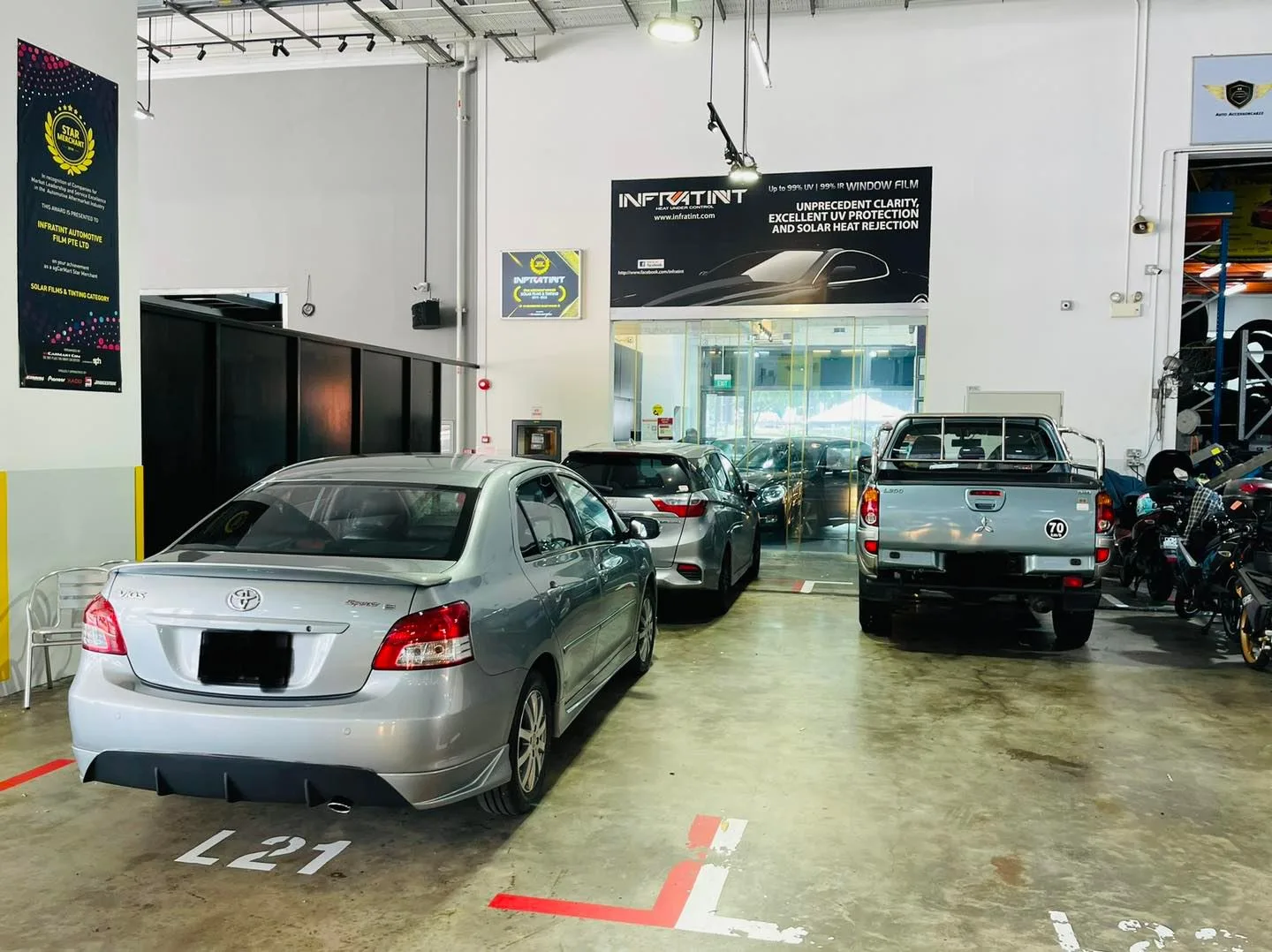 Silver Toyota sedan and a pickup truck parked in the install bay at Infratint Singapore
