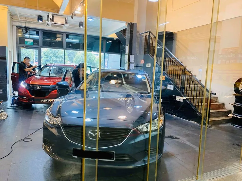 Grey Mazda 6 sedan and red Honda HR-V inside the Infratint Singapore showroom