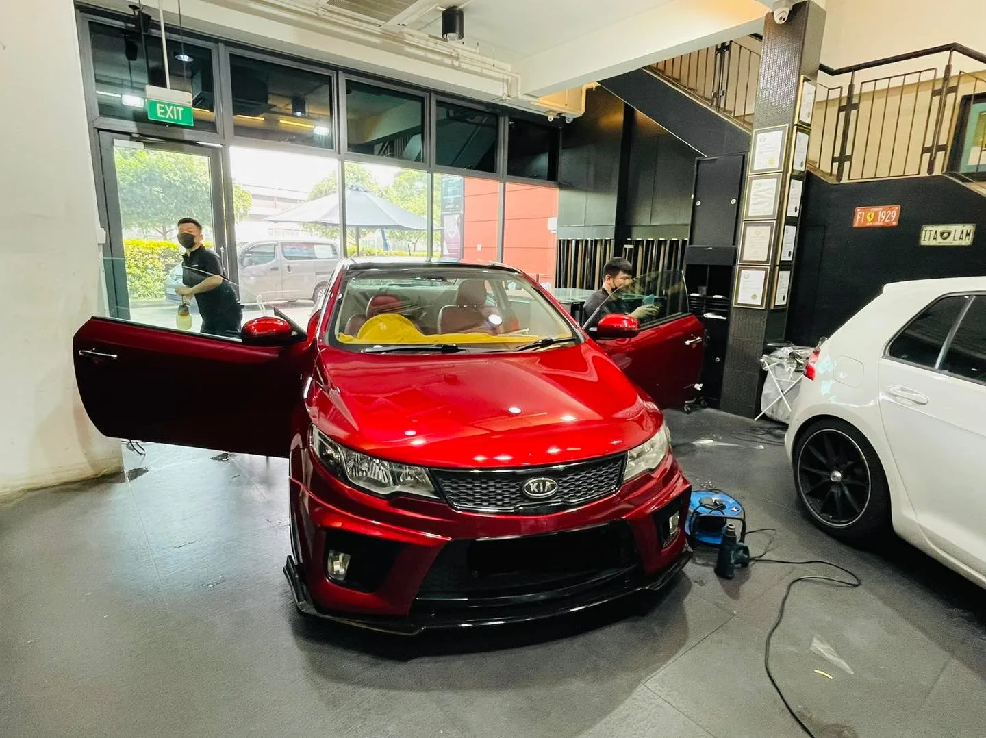 Red Kia Cerato with doors open during window tinting at Infratint Singapore
