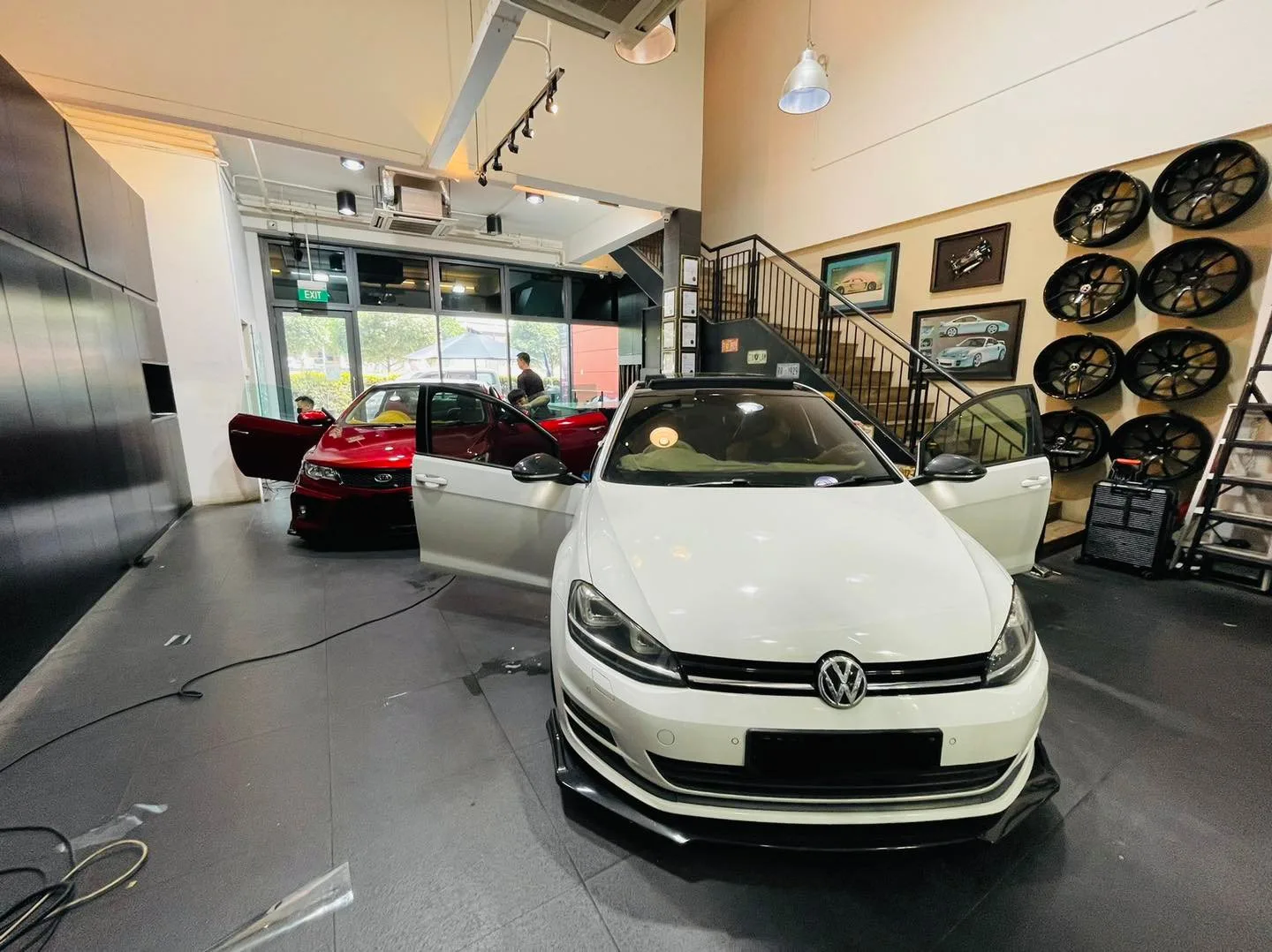 White Volkswagen Golf and red Kia with doors open at Infratint Singapore showroom