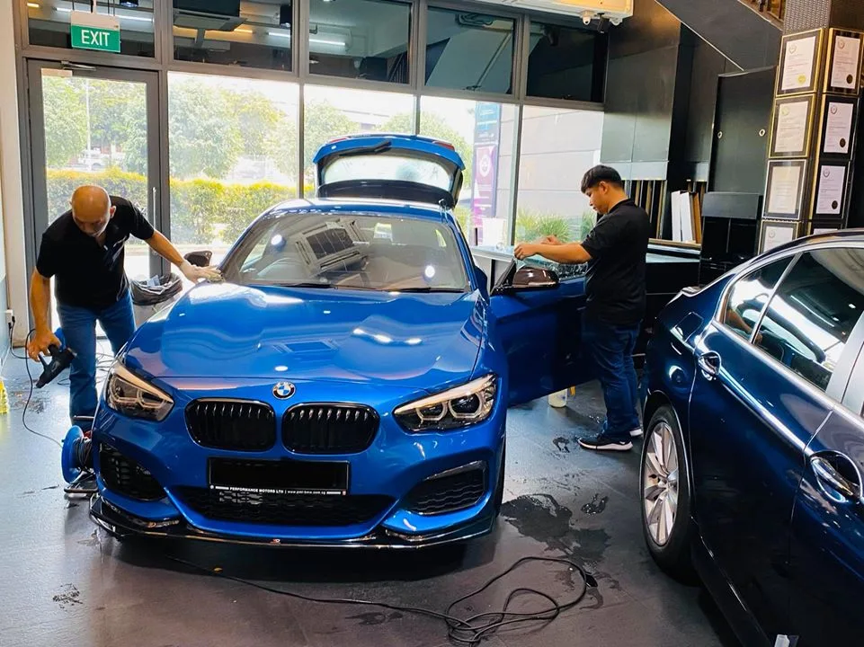 Blue BMW hatchback and a second blue BMW during window tinting at Infratint Singapore