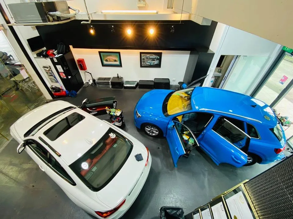 Overhead view of a blue Audi Q3 and white sedan being tinted at Infratint Singapore