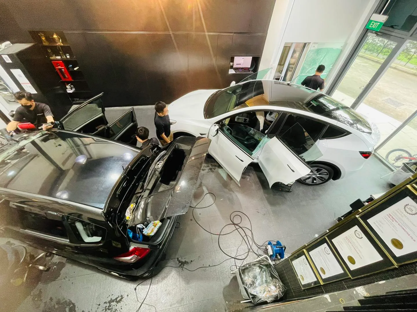 Team tinting a black SUV and white Tesla viewed from overhead at Infratint Singapore