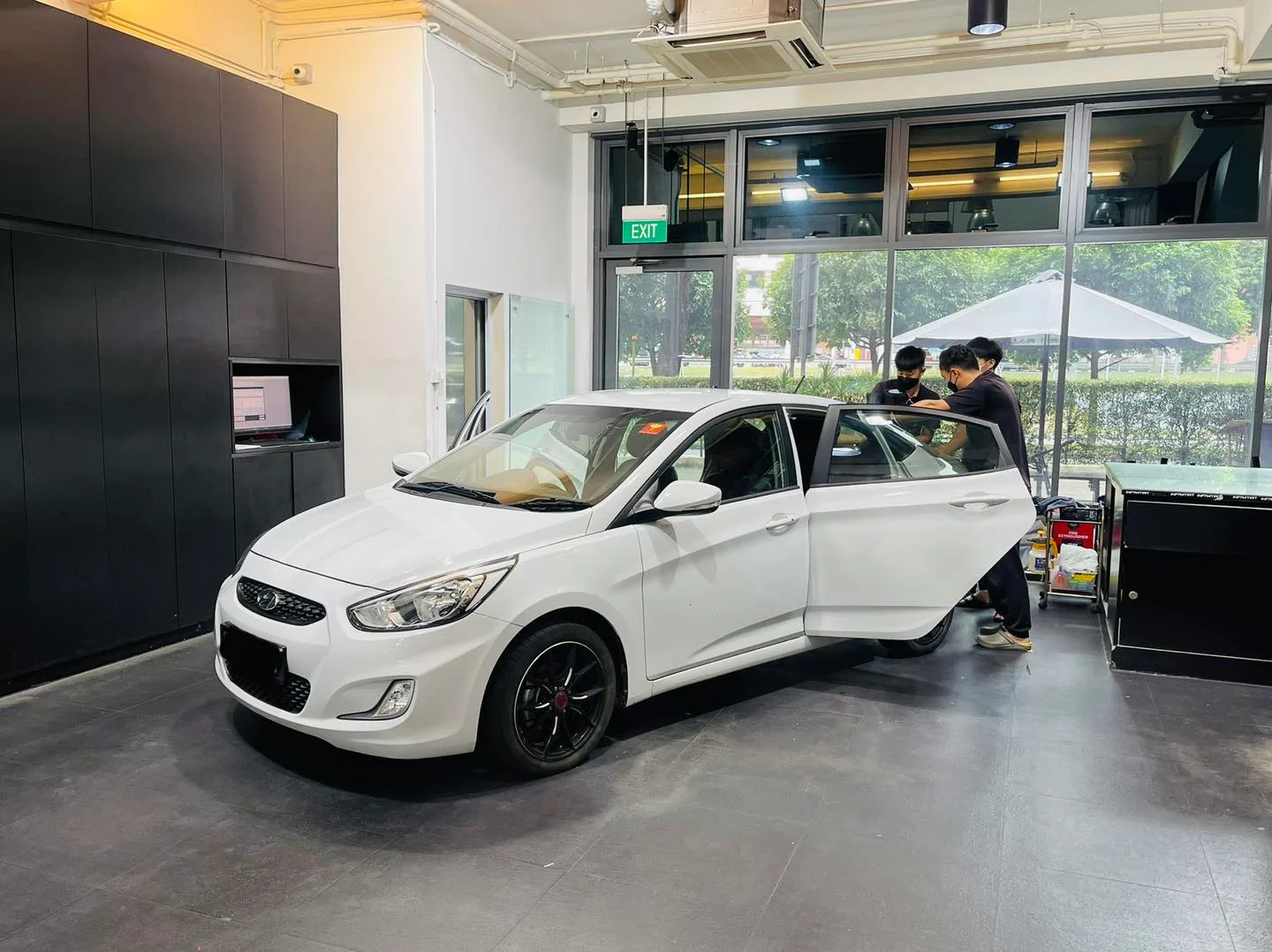 Installer fitting window film to a white Hyundai Accent at Infratint Singapore