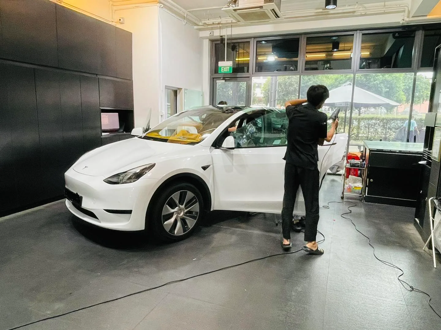 Installer applying window film to a white Tesla Model Y at Infratint Singapore