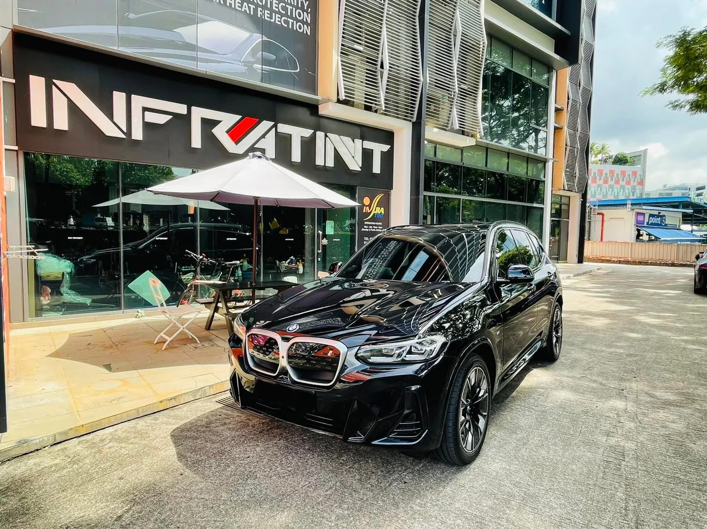 Black BMW SUV front three-quarter view outside the Infratint Singapore shopfront after tinting