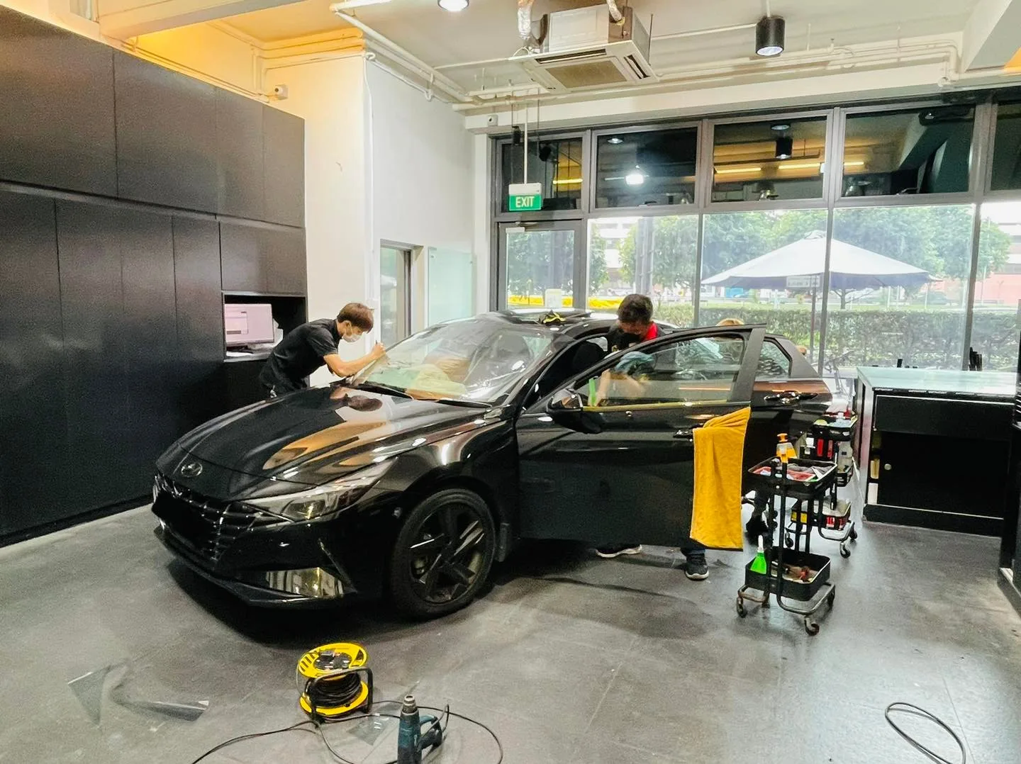 Black Hyundai sedan side view during window film installation at Infratint Singapore