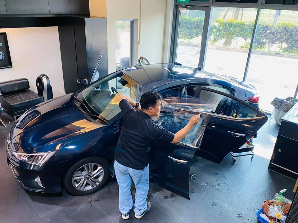Technician applying window film to a dark blue Hyundai at Infratint Singapore