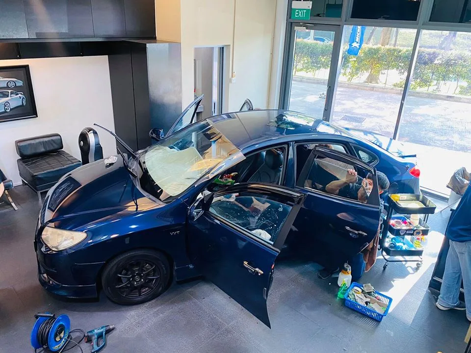 Overhead view of a blue Hyundai Avante with doors open during tinting at Infratint Singapore