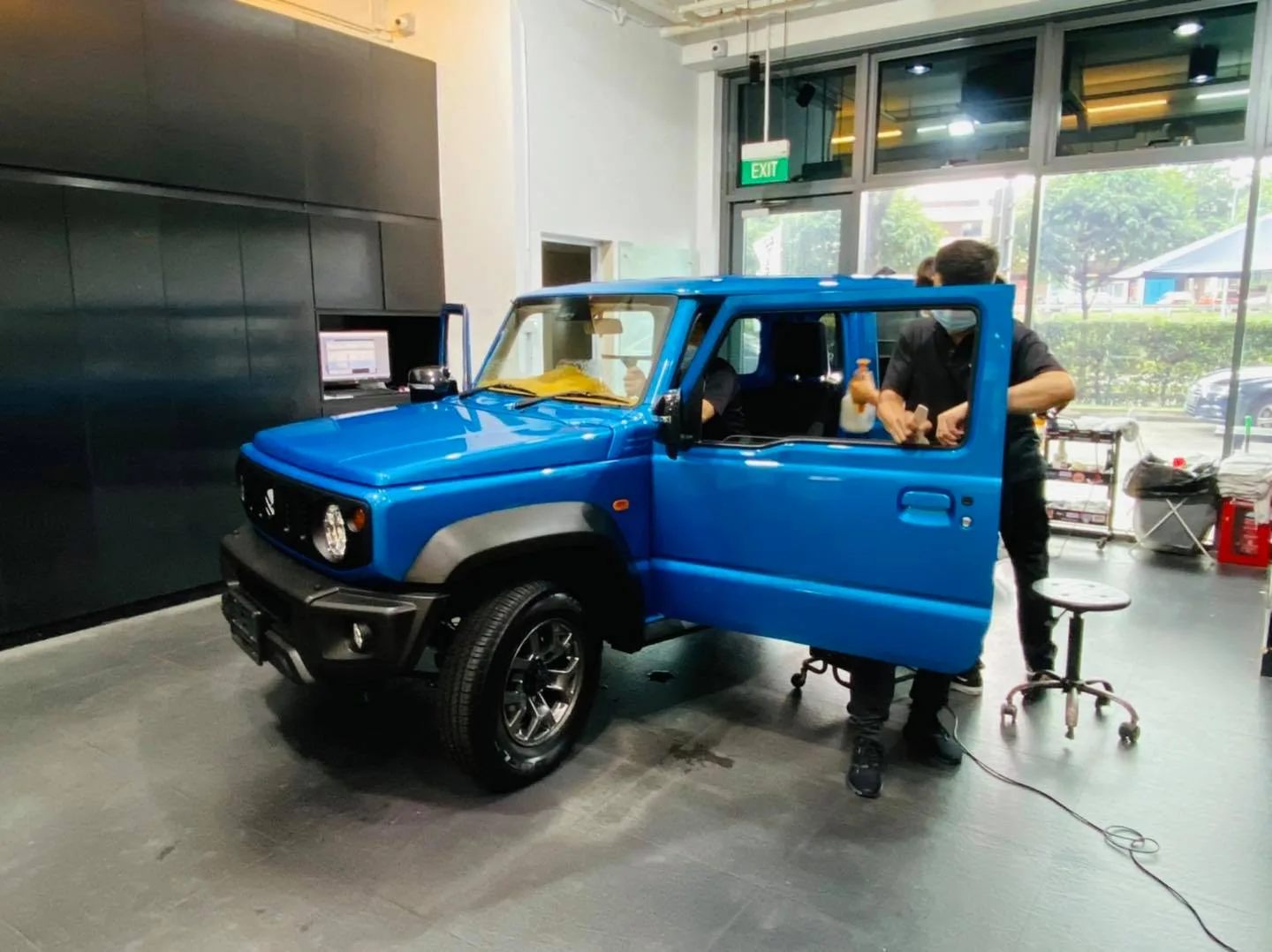 Tinter working on a blue Suzuki Jimny during window film installation at Infratint Singapore