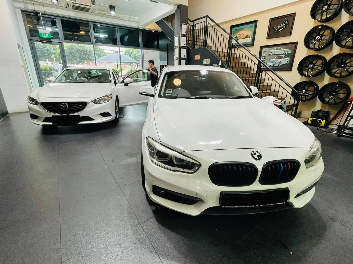 White BMW hatch and white Mazda sedan inside the Infratint Singapore showroom for tinting