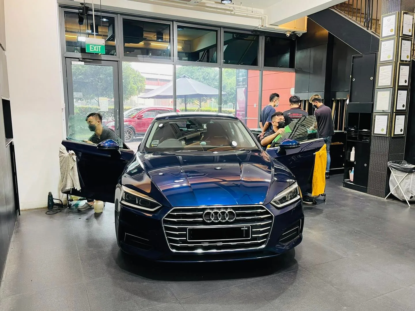 Blue Audi A5 surrounded by installers during window tinting at Infratint Singapore
