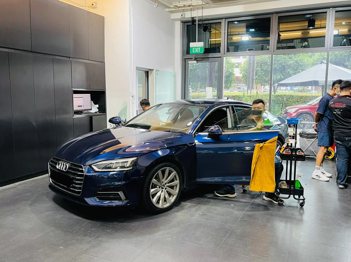 Installer tinting the door glass of a blue Audi sedan at Infratint Singapore