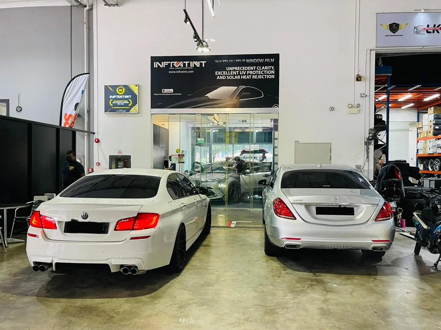 White BMW and silver Mercedes-Benz sedans in the Infratint Singapore install bay