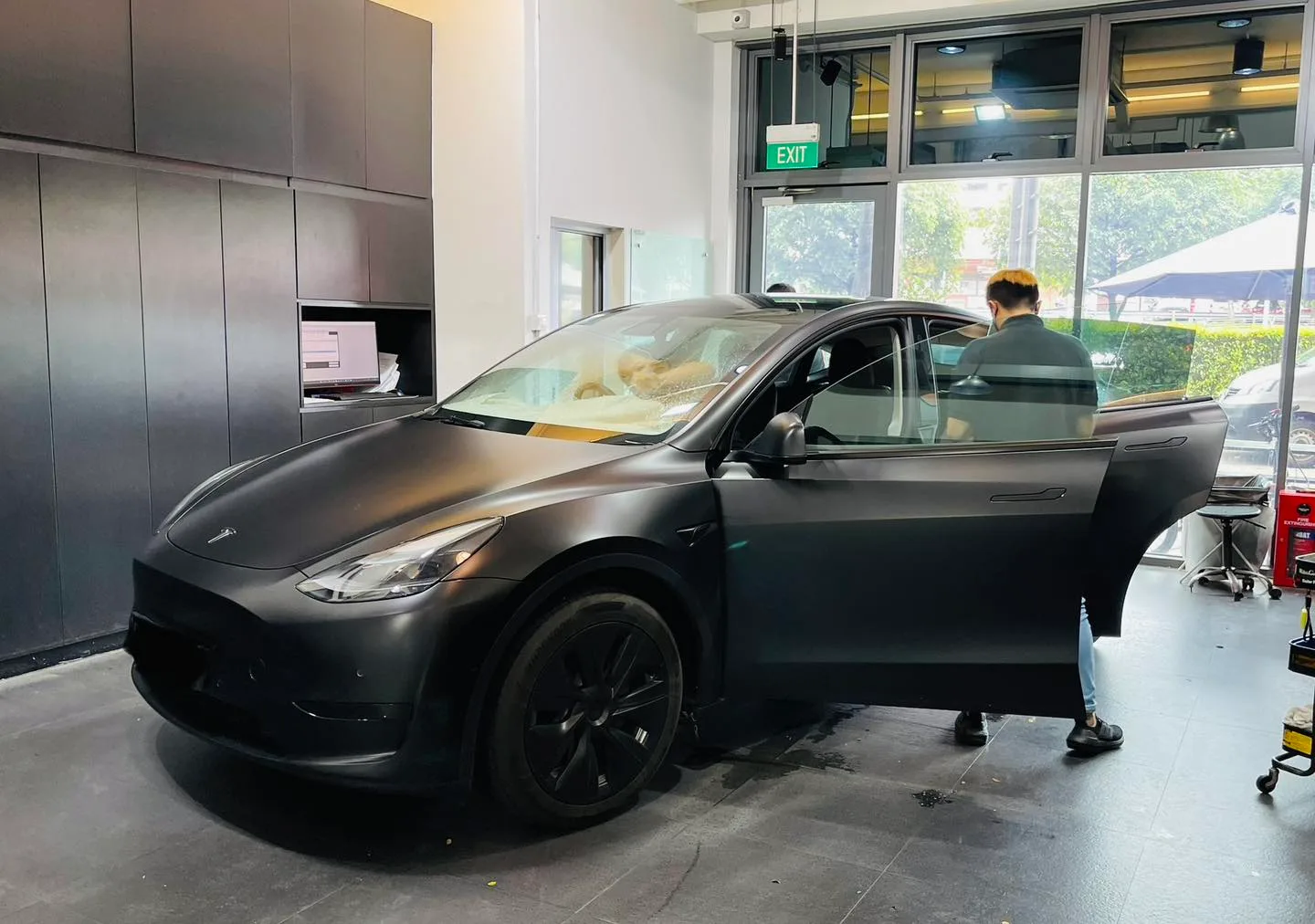 Matte black Tesla Model Y with rear door open during window tinting at Infratint Singapore