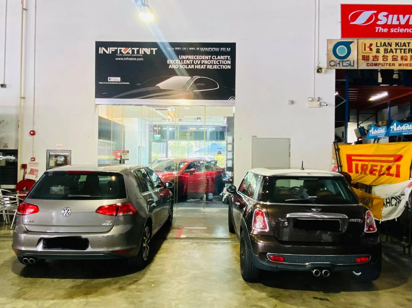 Grey Volkswagen Golf and a brown Mini Cooper S parked under the Infratint banner in Singapore