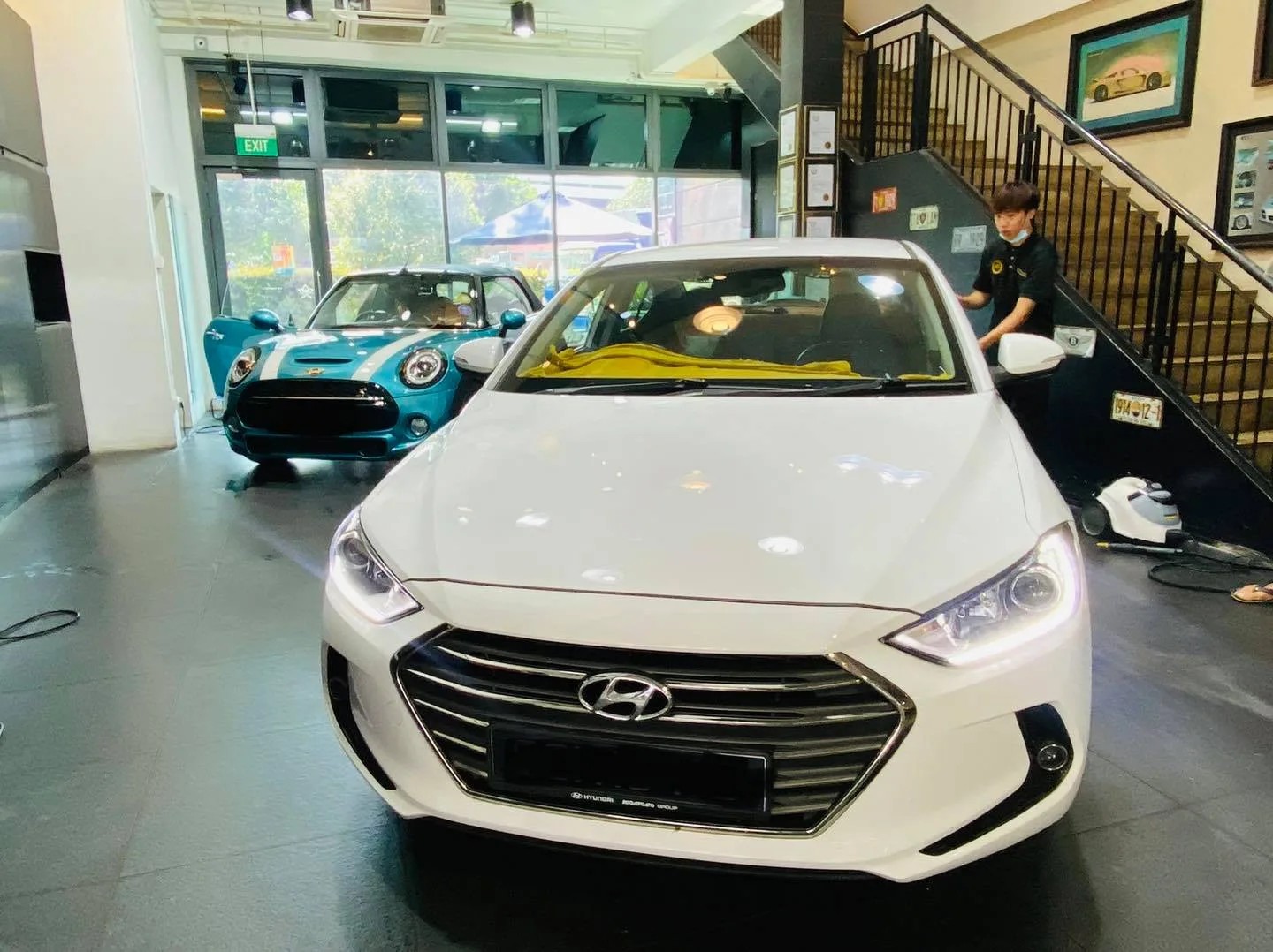 White Hyundai sedan front view at Infratint Singapore with a teal Mini behind