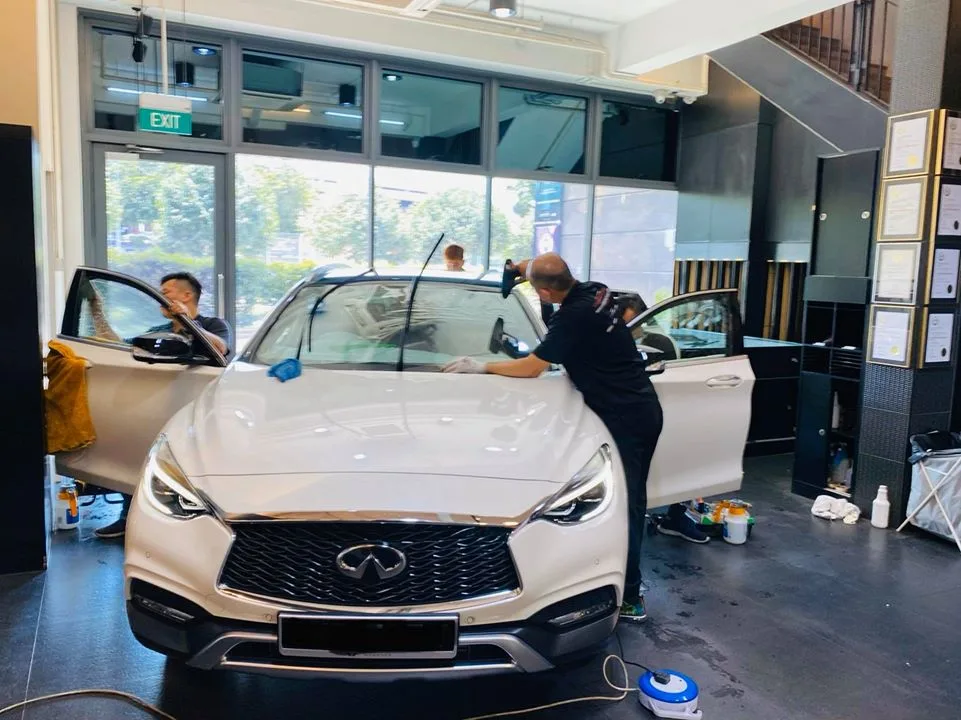 White Infiniti Q30 front grille with technicians working at Infratint Singapore