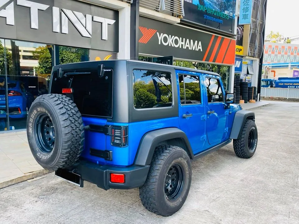 Rear view of a blue Jeep Wrangler Rubicon with spare tyre at Infratint Singapore
