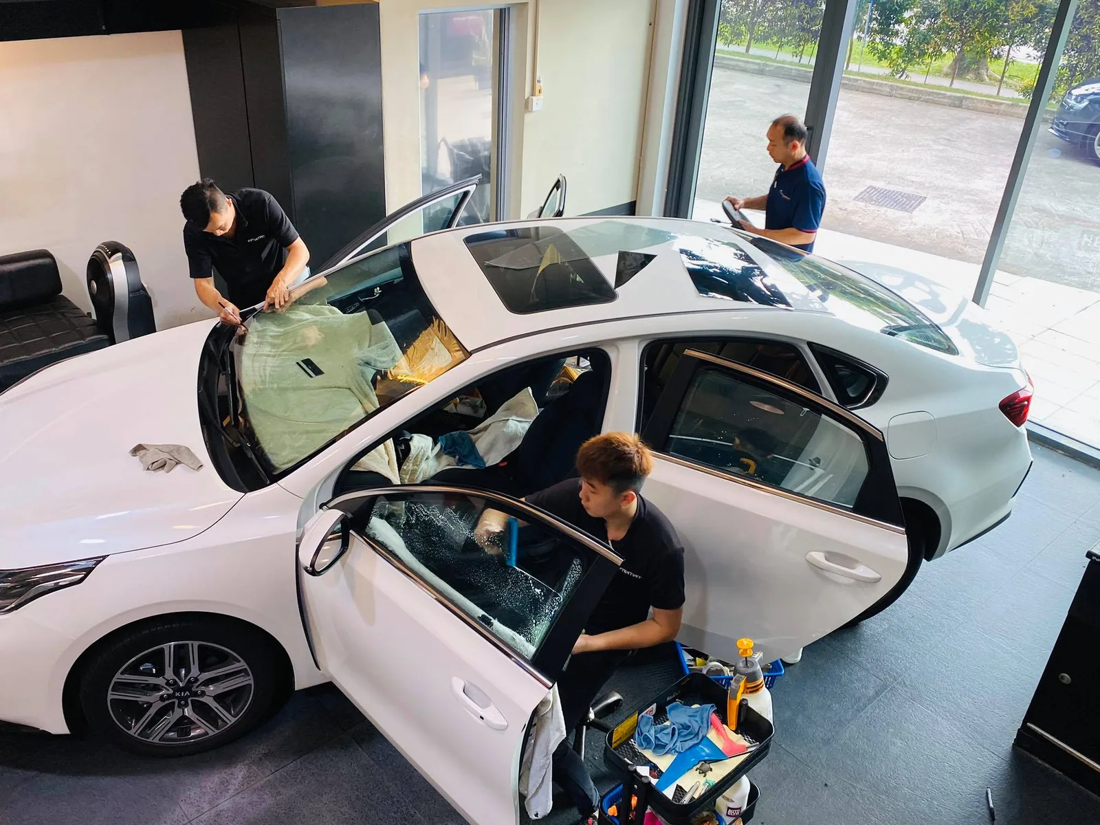 Technician applying window film to a white Kia Cerato door at Infratint Singapore