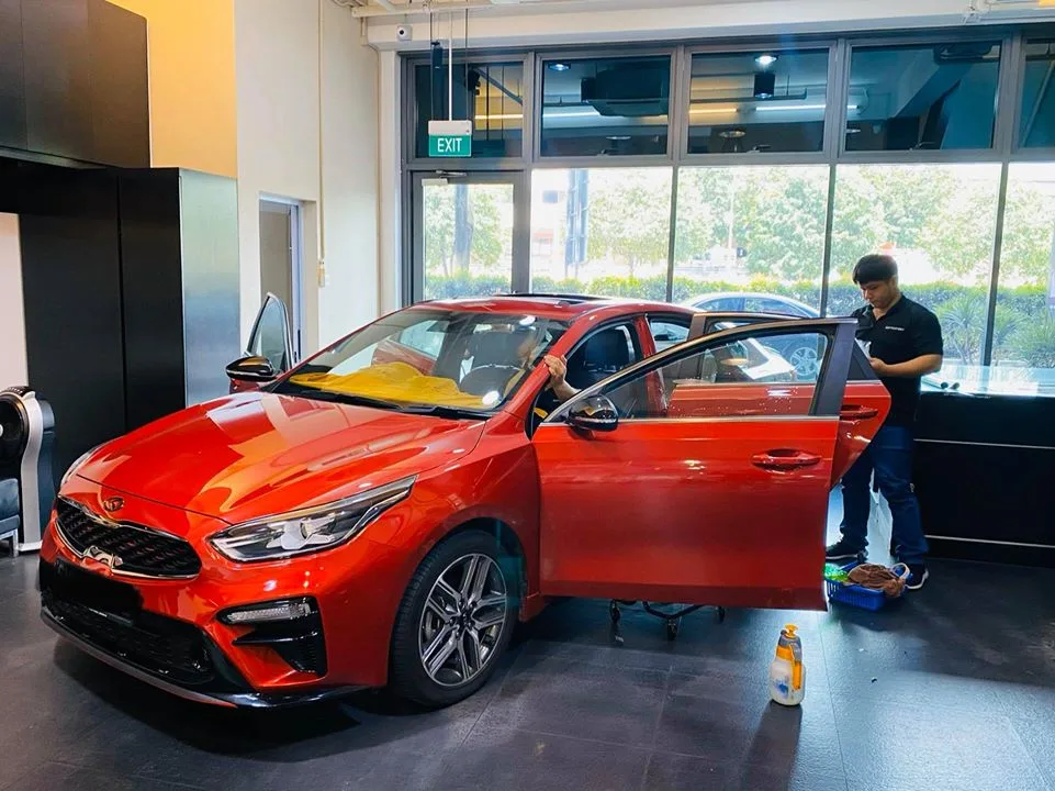 Technician installing window film on a red Kia Cerato side glass at Infratint Singapore