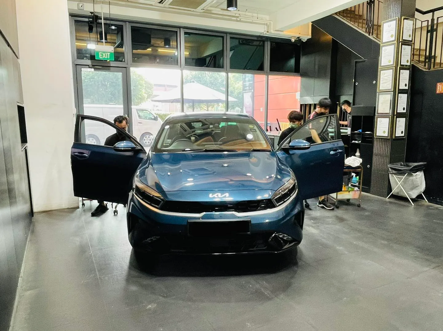 Blue Kia Cerato with doors open during window tinting at Infratint Singapore
