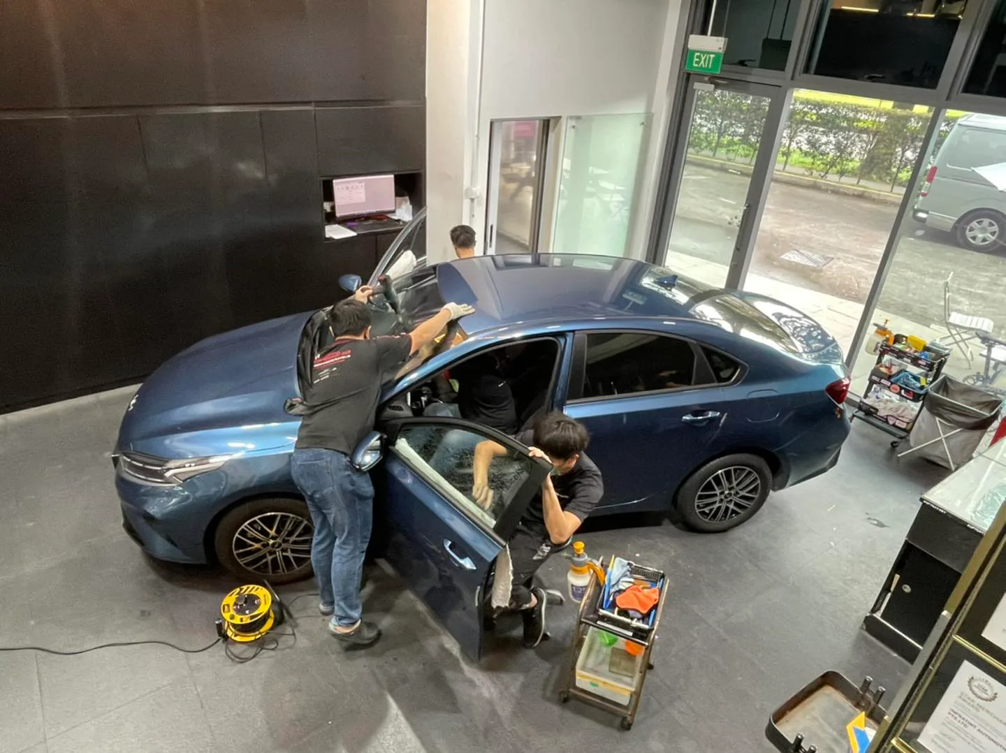 Overhead view of technicians tinting a blue Kia Cerato at Infratint Singapore