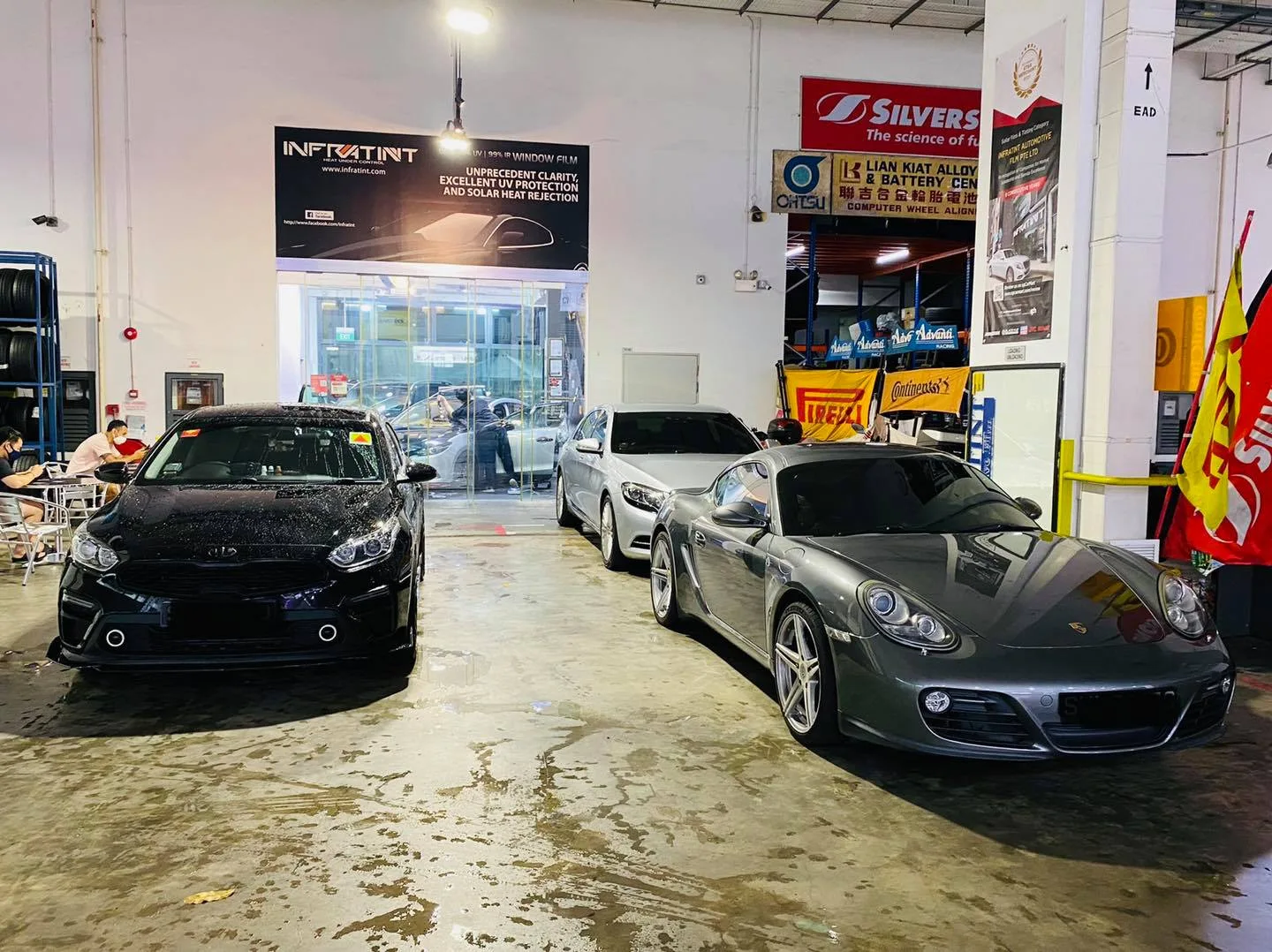 Black Kia Cerato and grey Porsche Cayman in the install bay at Infratint Singapore