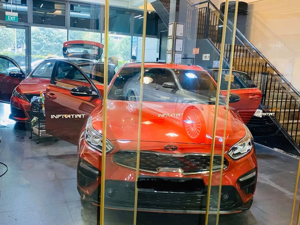 Orange Kia sedan with Infratint bonnet decal during window tinting at Infratint Singapore
