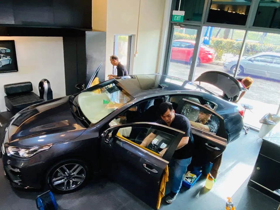 Technician installing window film on a grey Kia Cerato at Infratint Singapore