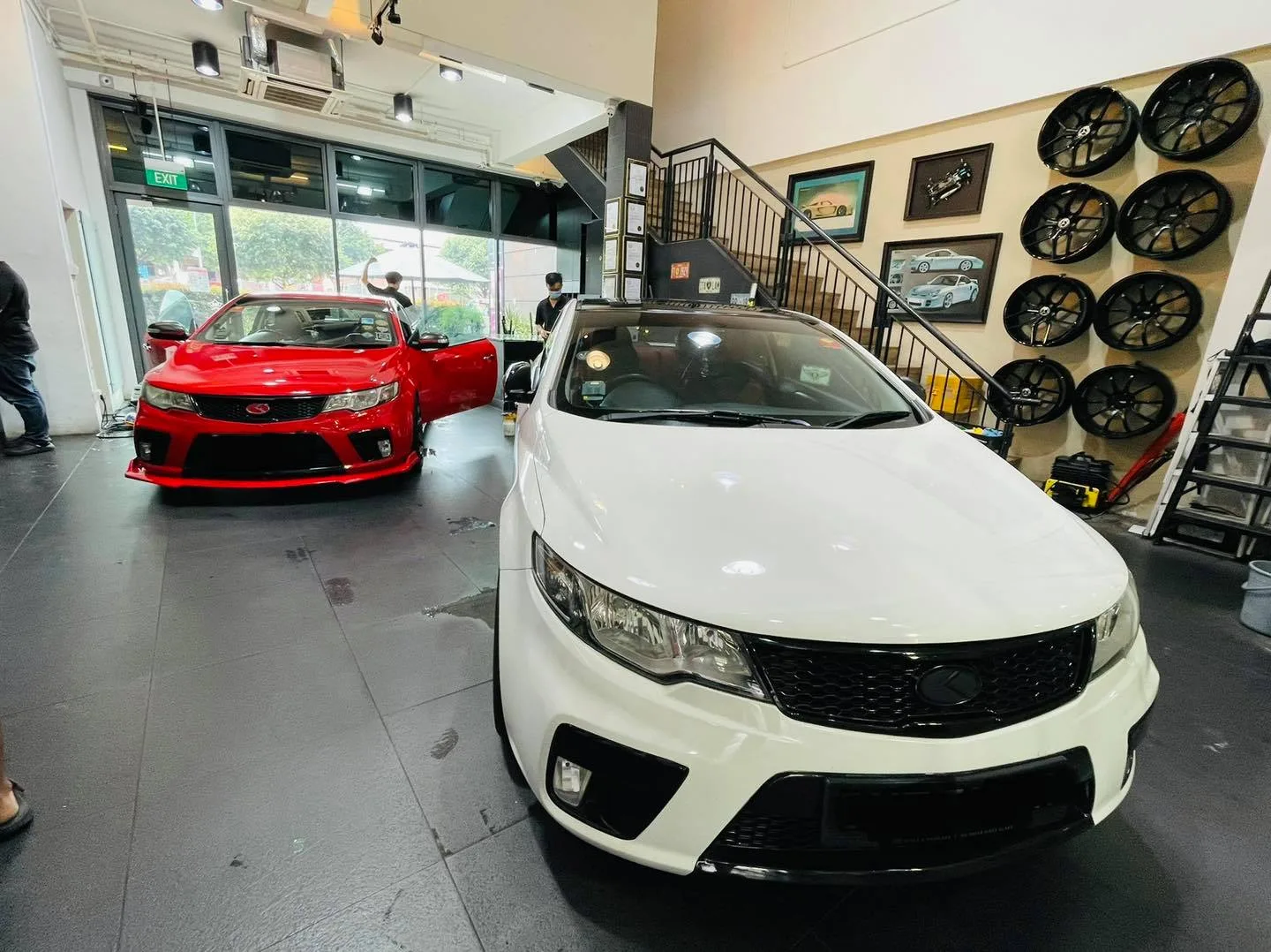 White Kia Forte and red coupe inside the Infratint Singapore showroom for window tinting